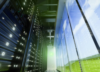 Interior view of a data center showing server racks and large windows with a view of the sky.