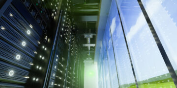 Interior view of a data center showing server racks and large windows with a view of the sky.