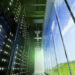 Interior view of a data center showing server racks and large windows with a view of the sky.