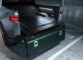Open tailgate of an electric pickup truck showing the cargo bed and interior lighting.