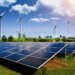 Rows of solar panels in a field with wind turbines in the background under a clear blue sky.