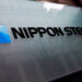 Nippon Steel company logo displayed on a glass surface with a blue geometric design.