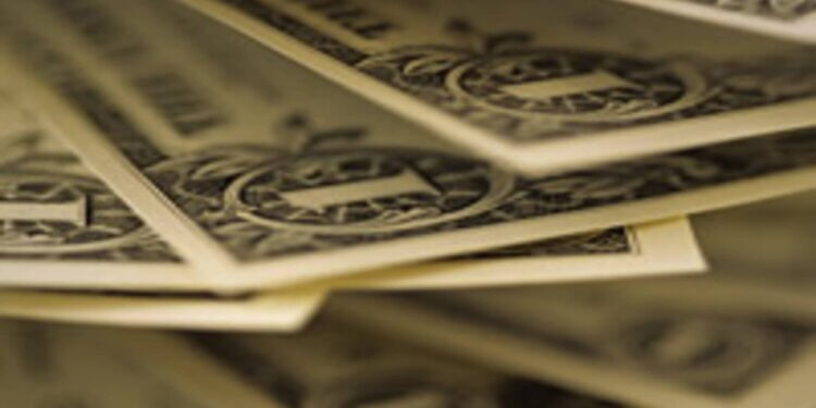 Close-up view of stacked dollar bills with detailed designs and serial numbers visible.