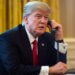 Donald Trump speaking on the phone while seated at a desk in the Oval Office.