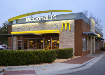 Exterior view of a McDonald's restaurant featuring the iconic golden arches and stone facade.