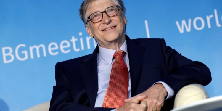 Bill Gates smiling while seated in a chair during a conference event.