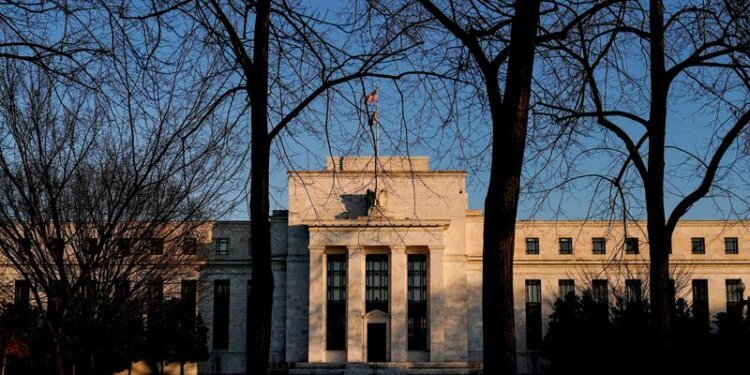 Federal Reserve building viewed through bare trees during sunset with clear sky.