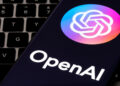 OpenAI logo displayed on a smartphone screen with a keyboard in the background.
