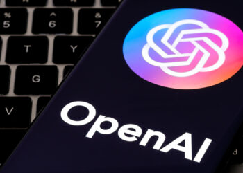 OpenAI logo displayed on a smartphone screen with a keyboard in the background.