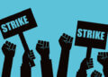 Illustration of multiple raised fists holding signs that say 'Strike' against a blue background.