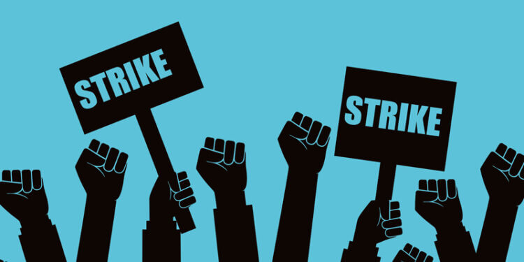 Illustration of multiple raised fists holding signs that say 'Strike' against a blue background.