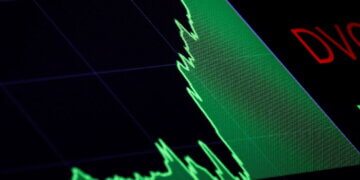 Stock market graph displaying a fluctuating line in green and red on a dark background.