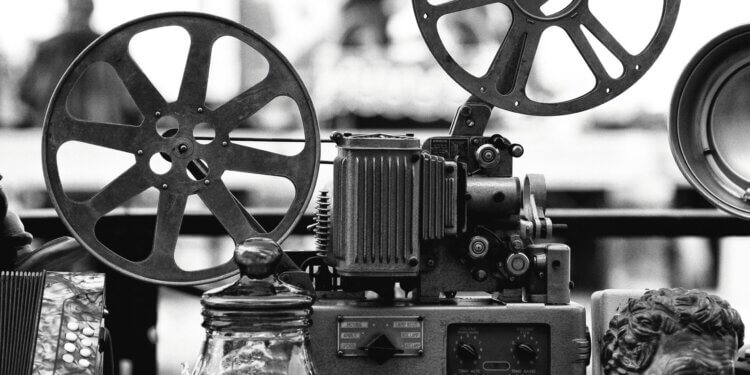 Close-up of a vintage film projector with two large film reels and mechanical components.