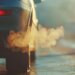 Close-up of a car tailpipe emitting thick exhaust gases in an urban setting.