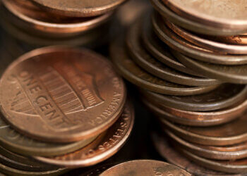 Close-up of a stack of copper coins, primarily showing one-cent coins in a disorganized arrangement.