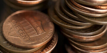 Close-up of a stack of copper coins, primarily showing one-cent coins in a disorganized arrangement.