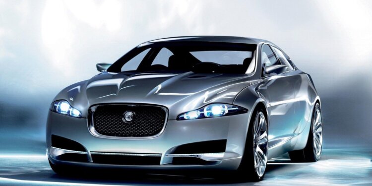 Silver Jaguar car model with sleek design and illuminated headlights on a neutral background.