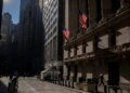 Exterior view of the New York Stock Exchange building with American flags displayed.