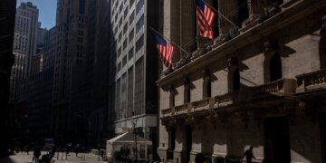 Exterior view of the New York Stock Exchange building with American flags displayed.