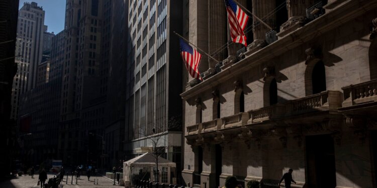 Exterior view of the New York Stock Exchange building with American flags displayed.