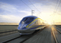 A high-speed train traveling on tracks with a blurred background of landscape and sunrise.