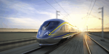 A high-speed train traveling on tracks with a blurred background of landscape and sunrise.
