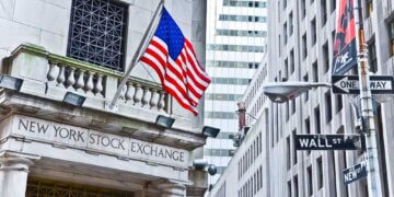 Exterior view of the New York Stock Exchange building featuring an American flag and street signs.