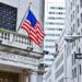 Exterior view of the New York Stock Exchange building featuring an American flag and street signs.