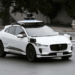 White Waymo autonomous vehicle with sensors and cameras parked on a city street.