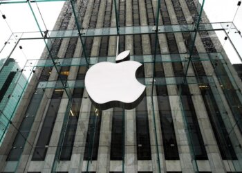 Glass facade of an Apple Store featuring the large Apple logo prominently displayed.