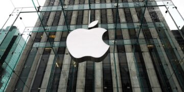 Glass facade of an Apple Store featuring the large Apple logo prominently displayed.