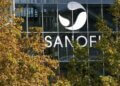 Sanofi logo displayed prominently on the glass facade of a building surrounded by trees.