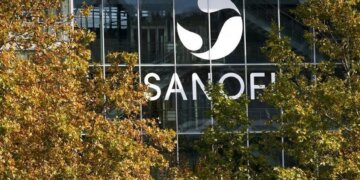 Sanofi logo displayed prominently on the glass facade of a building surrounded by trees.