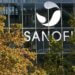 Sanofi logo displayed prominently on the glass facade of a building surrounded by trees.