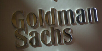 Metallic sign displaying the name 'Goldman Sachs' in a corporate setting.