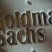 Metallic sign displaying the name 'Goldman Sachs' in a corporate setting.