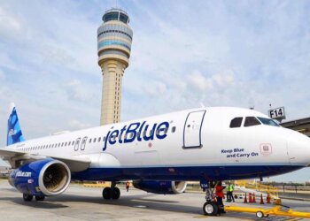 JetBlue Airways aircraft parked at an airport with a control tower in the background.