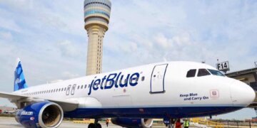 JetBlue Airways aircraft parked at an airport with a control tower in the background.