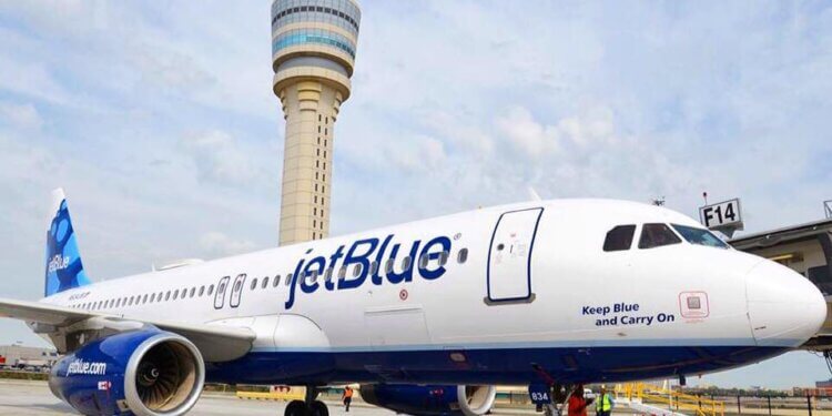 JetBlue Airways aircraft parked at an airport with a control tower in the background.