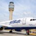 JetBlue Airways aircraft parked at an airport with a control tower in the background.