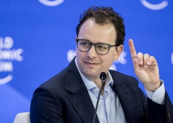 A man with glasses raising his finger while speaking at the World Economic Forum event.