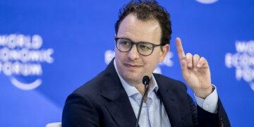 A man with glasses raising his finger while speaking at the World Economic Forum event.