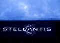Stellantis logo illuminated on a large screen against a cloudy sky.