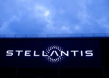 Stellantis logo illuminated on a large screen against a cloudy sky.