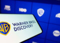 Warner Bros. Discovery logo displayed on a smartphone with a blue interface in the background.