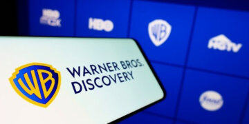 Warner Bros. Discovery logo displayed on a smartphone with a blue interface in the background.