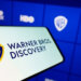 Warner Bros. Discovery logo displayed on a smartphone with a blue interface in the background.