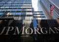 Close-up of the JP Morgan sign on a building with glass architecture in the background.