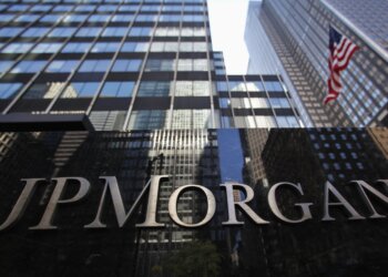 Close-up of the JP Morgan sign on a building with glass architecture in the background.