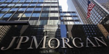 Close-up of the JP Morgan sign on a building with glass architecture in the background.